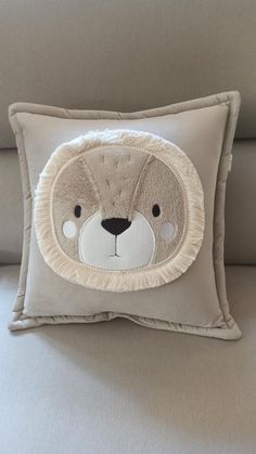 a pillow with a teddy bear on it's face is sitting on a couch