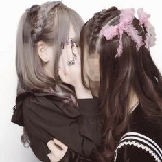 two women with long hair are hugging each other and one has her hand on her face