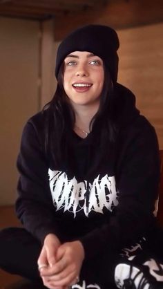 a woman sitting on the floor wearing a black hoodie