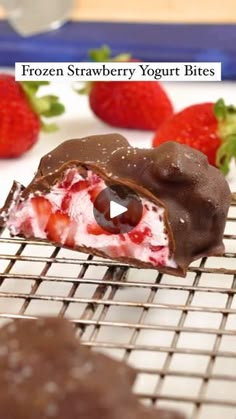 a chocolate covered strawberry yogurt bites on a cooling rack with strawberries in the background