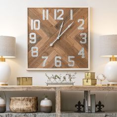 a large wooden clock mounted to the side of a wall next to lamps and books