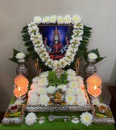 the altar is decorated with white flowers and silver vases, candles, and a painting