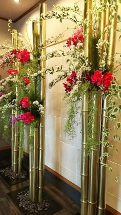 three tall gold vases with flowers in them