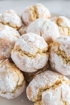 a pile of powdered sugar cookies sitting on top of a white plate