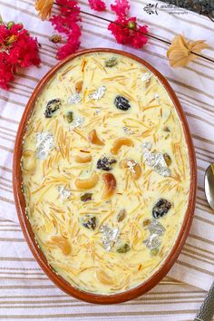 a bowl filled with cheese and nuts on top of a striped table cloth next to flowers