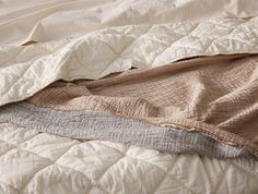 an unmade bed with white and brown sheets