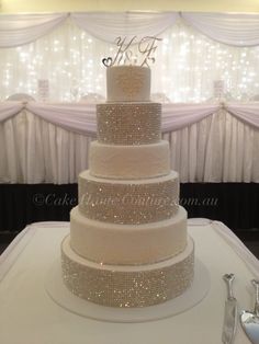 a wedding cake sitting on top of a table next to a white cloth covered wall