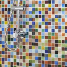 a shower head with colorful tiles in the background