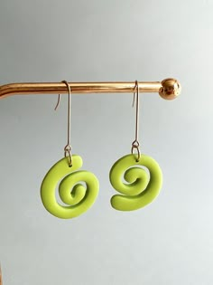 green earrings with spiral design hanging from hooks