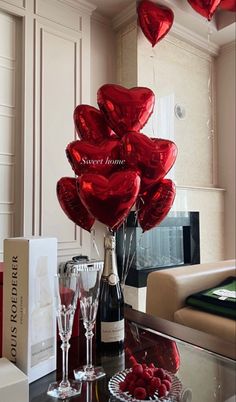 red heart balloons in the shape of hearts on a table with wine glasses and champagne