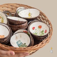 a person holding a basket full of old china plates and bowls with flowers painted on them