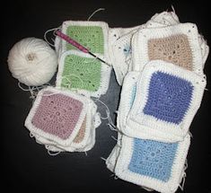 four crocheted squares are sitting on the table next to a ball of yarn