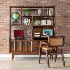 a chair and desk in front of a brick wall with bookshelves on it