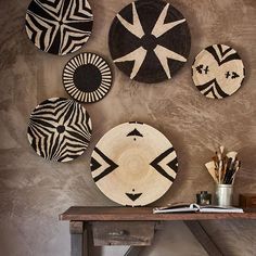 several black and white plates hanging on the wall above a wooden table with stools