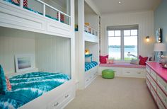 a bedroom with two bunk beds and a pink desk in front of the window that overlooks the water