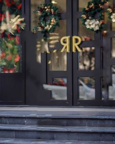 a woman walking down the street in front of a building with wreaths on it