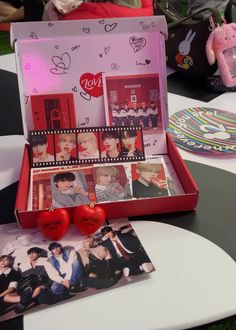 an open box with photos and hearts on the table in front of other items including a stuffed animal