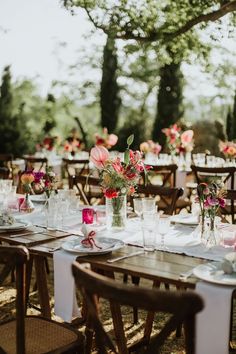 the tables are set with vases and flowers on them for an outdoor wedding reception