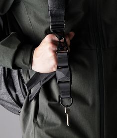 a person wearing a green jacket with a black belt around their waist and holding a key in his pocket