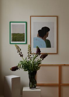 a vase filled with flowers sitting on top of a white table next to a painting