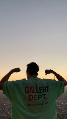 a man standing on top of a tall building with his hands up in the air