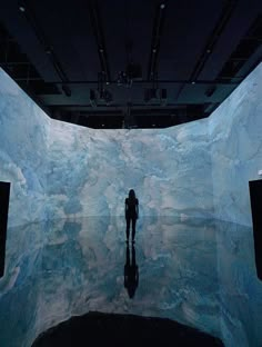 a person standing in front of an ice wall with water and clouds on the walls