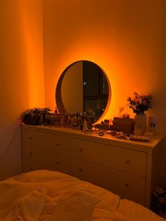 a bedroom scene with focus on the dresser and round mirror over which is lit up