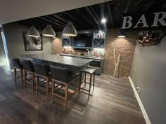 an open concept kitchen and dining area with bar stools in the foreground, dark wood flooring on the other side