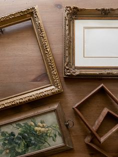 four framed pictures on a wooden table next to two frames with flowers painted on them