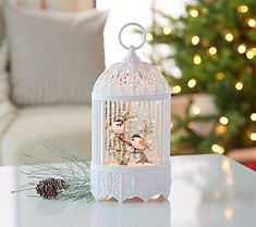 a white birdcage sitting on top of a table next to a pine cone