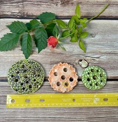 three different colored buttons sitting on top of a wooden table next to a measuring tape