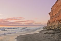 a beach with waves coming in to the shore and a cliff on the other side