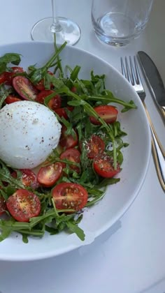 a white plate topped with salad and an egg