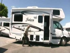 a man walking towards an rv parked in a parking lot