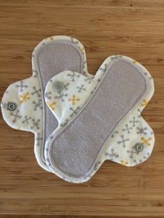 two baby bibs sitting on top of a wooden table