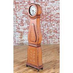 a wooden grandfather clock sitting on top of a hard wood floor next to a brick wall