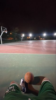 a person laying on the ground with a basketball in their hand and lights behind them