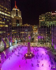 people skating on an ice rink in the city at night