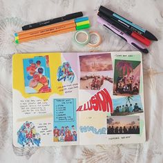 an open book with various pictures and pens on it next to markers, pencils, and paper