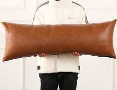 a man holding a large brown leather pillow