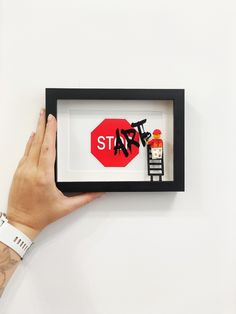 a hand is holding up a shadow box with the word stop painted on it