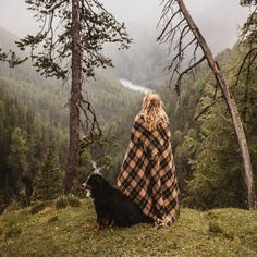 a woman sitting on top of a hill next to a dog