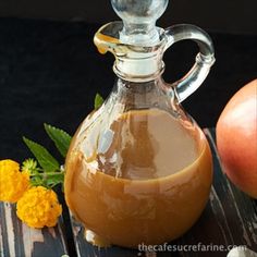 a glass bottle filled with liquid sitting on top of a table next to an apple