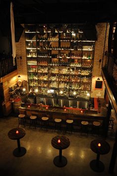 a dimly lit bar with several stools and bottles on the wall in front of it