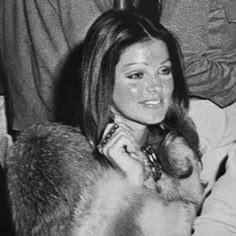 black and white photograph of a woman holding a fur coat