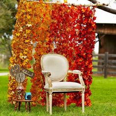 an old chair sitting in the grass near a tree with autumn leaves on it and a sign that says welcome