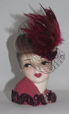 a mannequin head wearing a hat with feathers on it