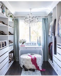 a closet with white shelves and chandelier hanging from the ceiling, filled with shoes