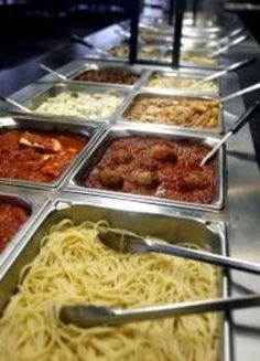 many trays of food are lined up on the buffet table with spoons in them