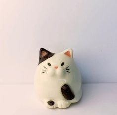 a white cat figurine sitting on top of a table next to a wall